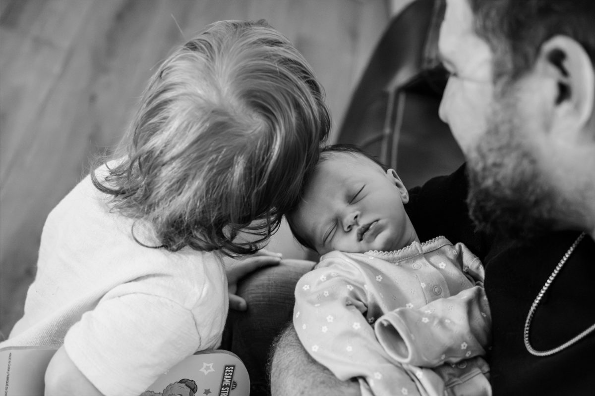 Big brother rubs his head along his baby sister's during a candid documentary photo session in Victoria BC