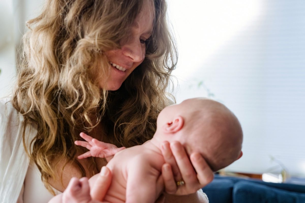 A soft and candid photo of a mother holding her newborn baby taken during a candid at-home photo session near Victoria BC