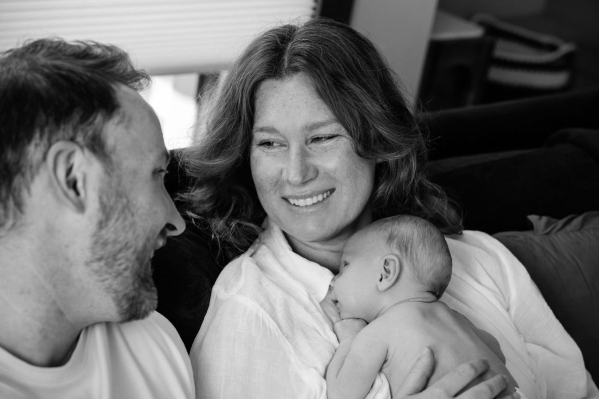 Parents smile at each other while holding their baby during a candid newborn session in Victoria BC