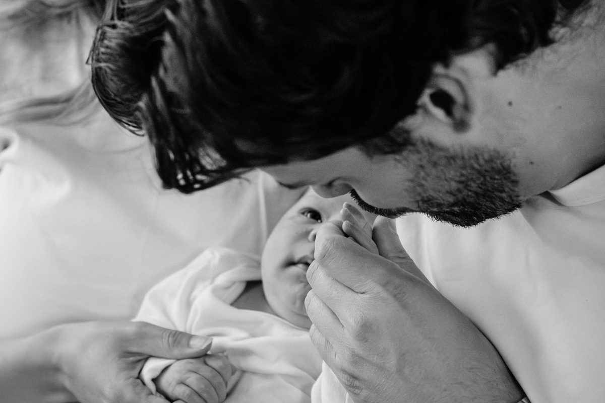 A father kisses his baby daughter's hand during a newborn session in Victoria BC