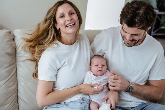 A couple holds their baby on their couch during their at home Victoria BC candid newborn mini session.