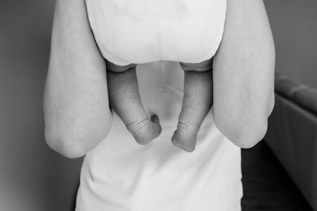 A unique newborn candid photo in Victoria BC of baby's feet being held by her mother.