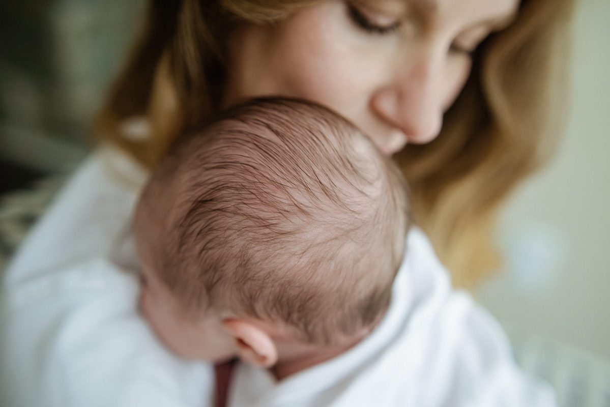 Motherhood photo in Victoria BC of a newborn being held.