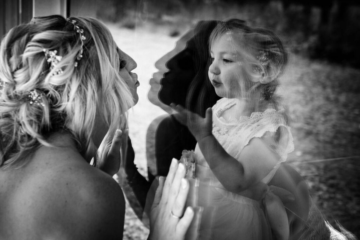 A mom kisses at her daughter in a window during her Hatley Castle wedding in Victoria C