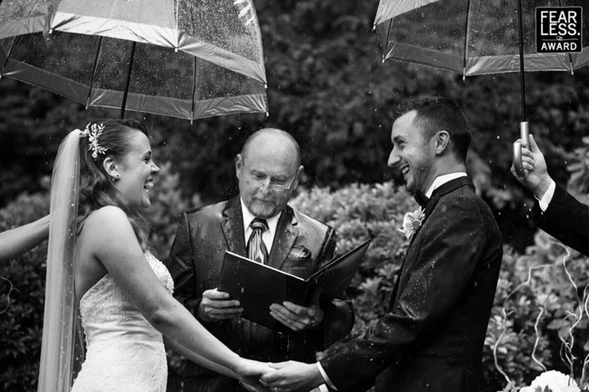 A couple has umbrellas over their heads at their outdoor wedding in a backyard in Victoria BC
